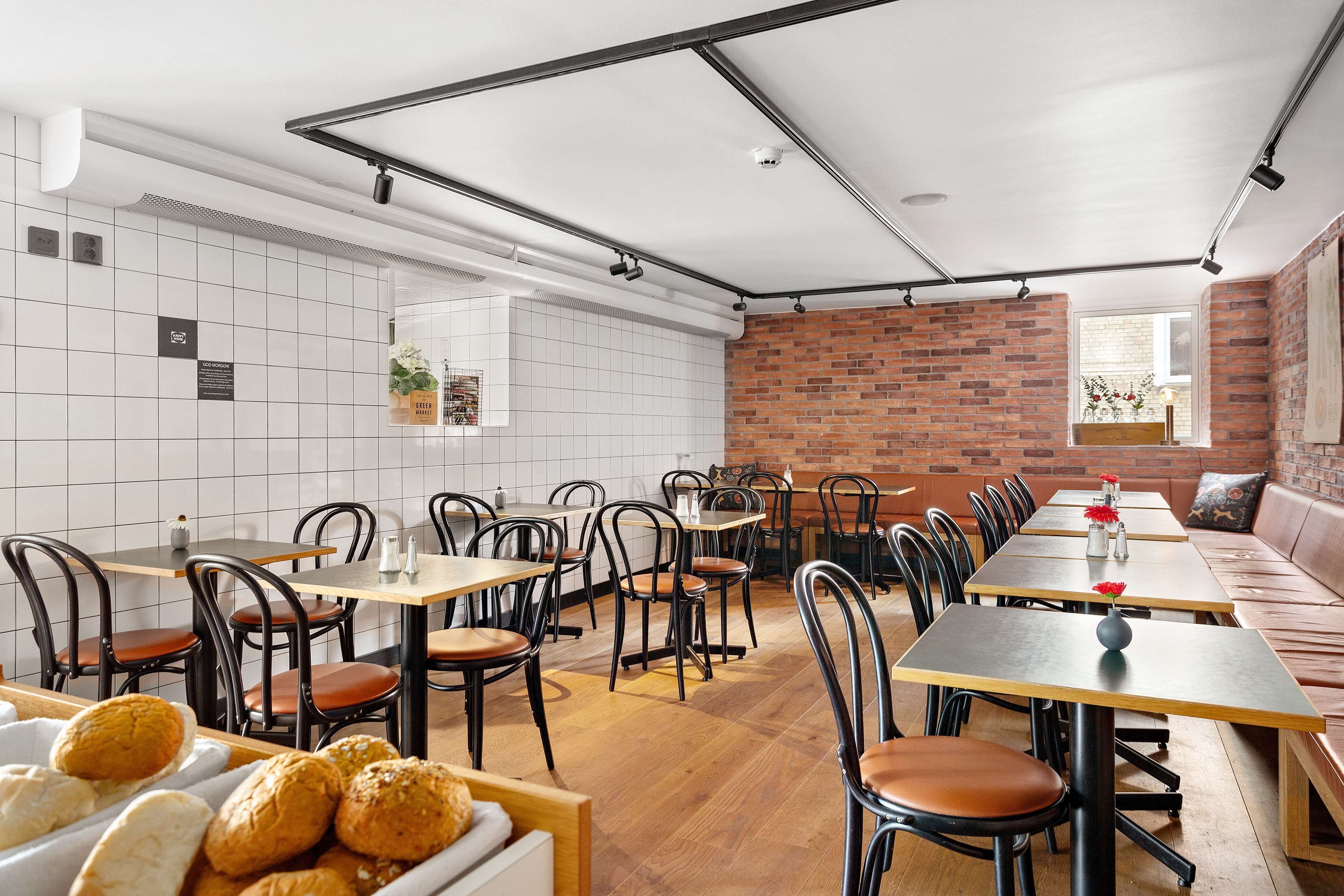 Een restaurant met bakstenen muren, betegelde vloeren en een combinatie van houten en metalen meubels.