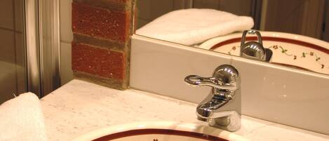Un baño con un lavabo blanco, un espejo y una pared de ladrillo rojo.