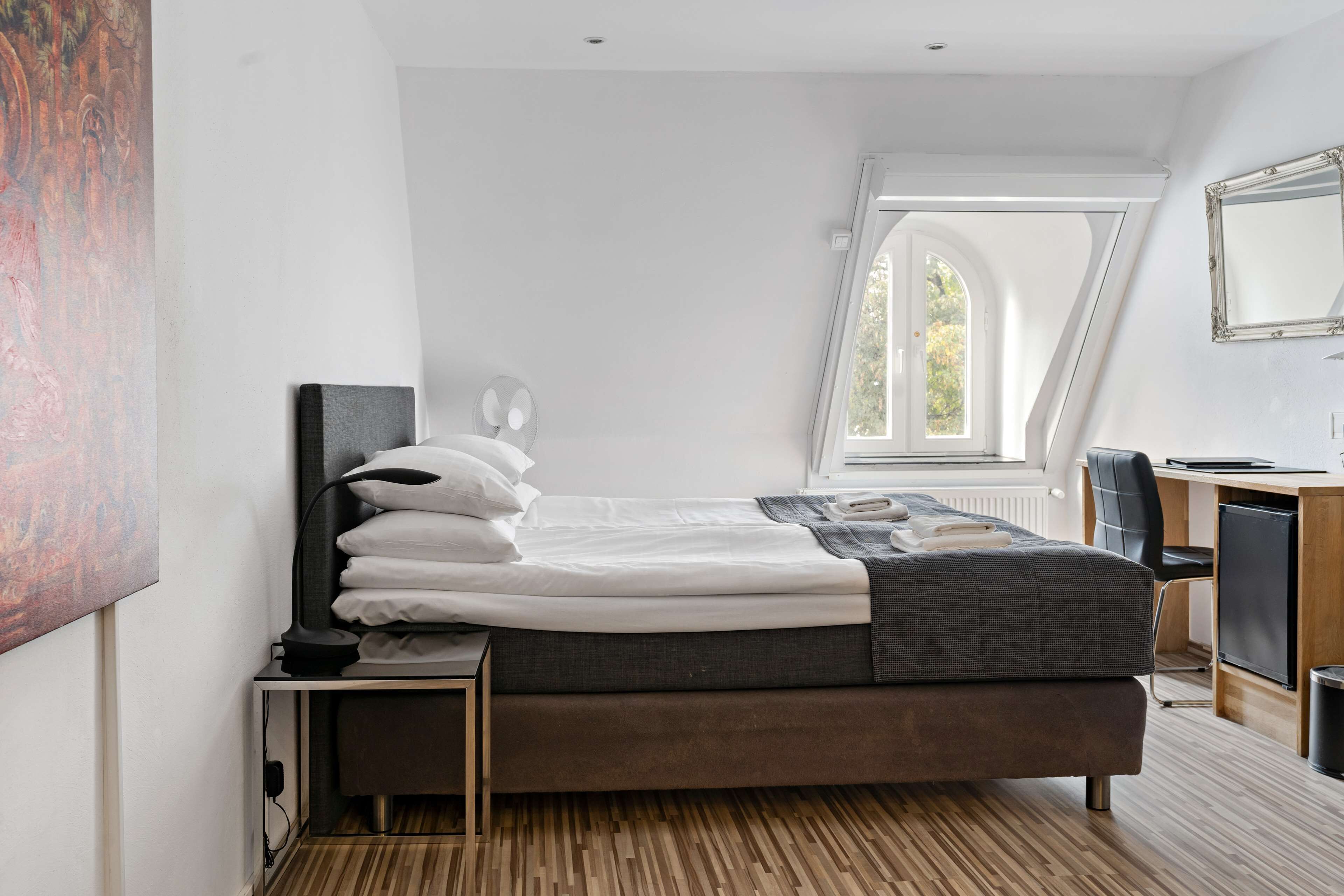 Un dormitorio moderno con cama, mesita de noche, lámpara y escritorio con silla.
