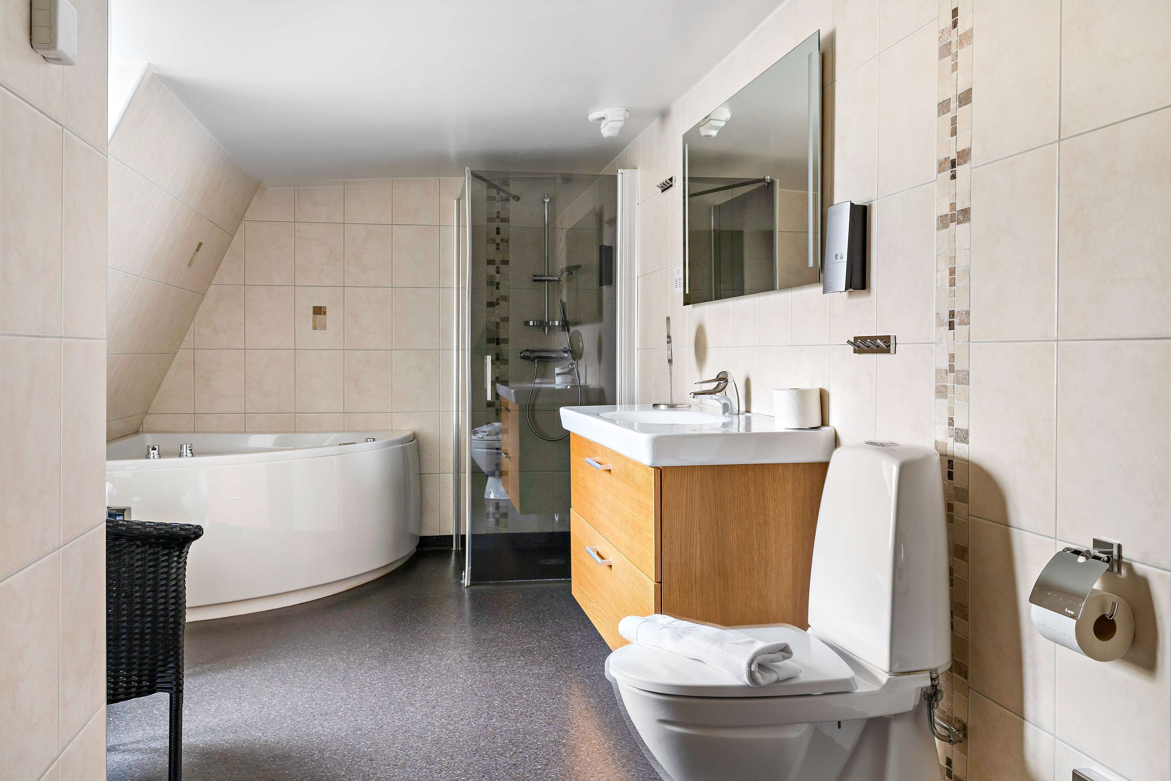 Un baño moderno con una bañera independiente, un inodoro y un tocador con espejo.