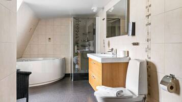 Un baño moderno con una bañera independiente, un inodoro y un tocador con espejo.