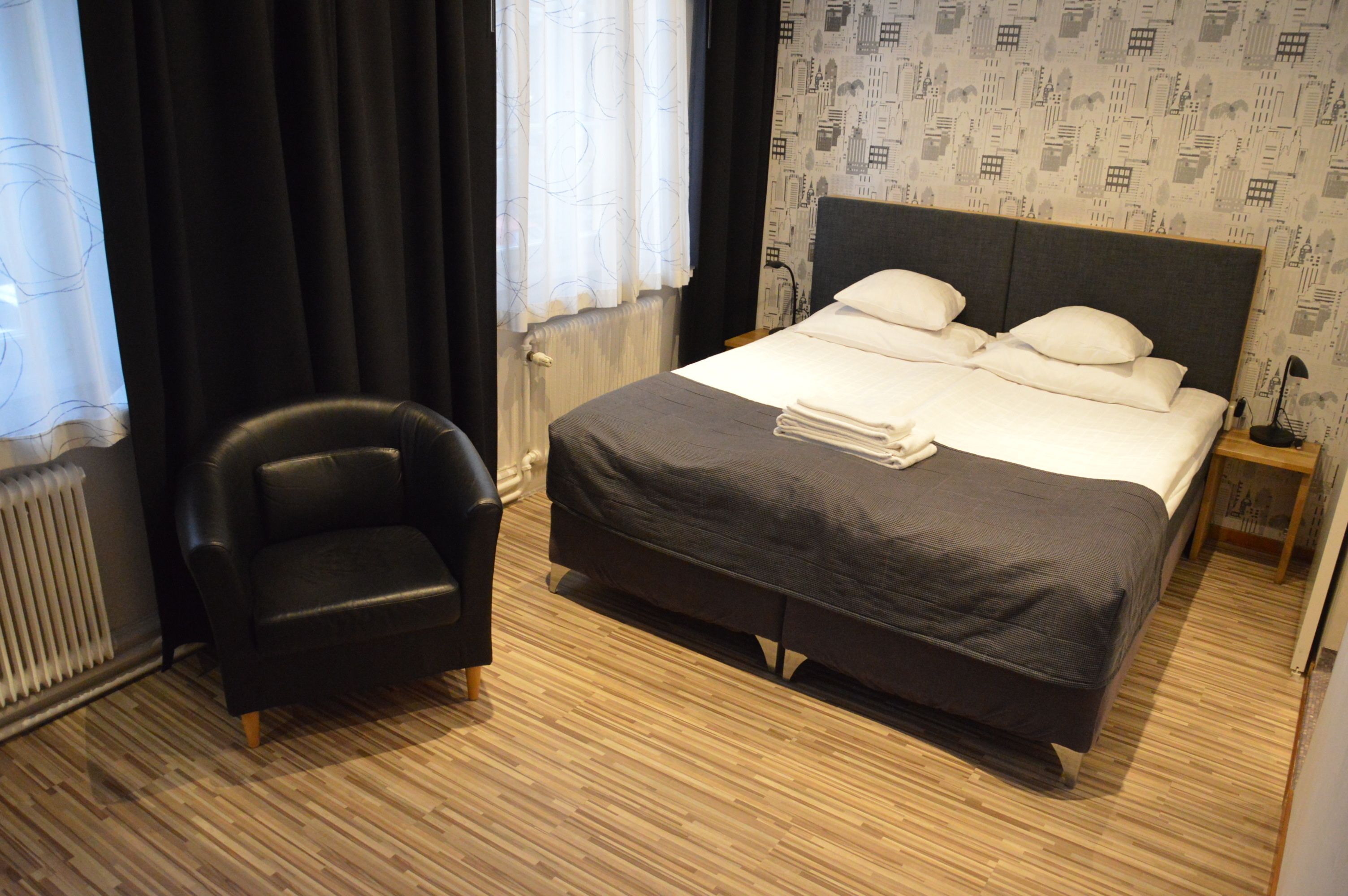 A hotel room with a bed, a chair, and a radiator.