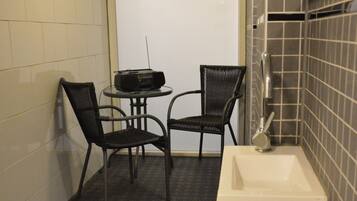 Et lille badeværelse med vask, to stole og et bord.