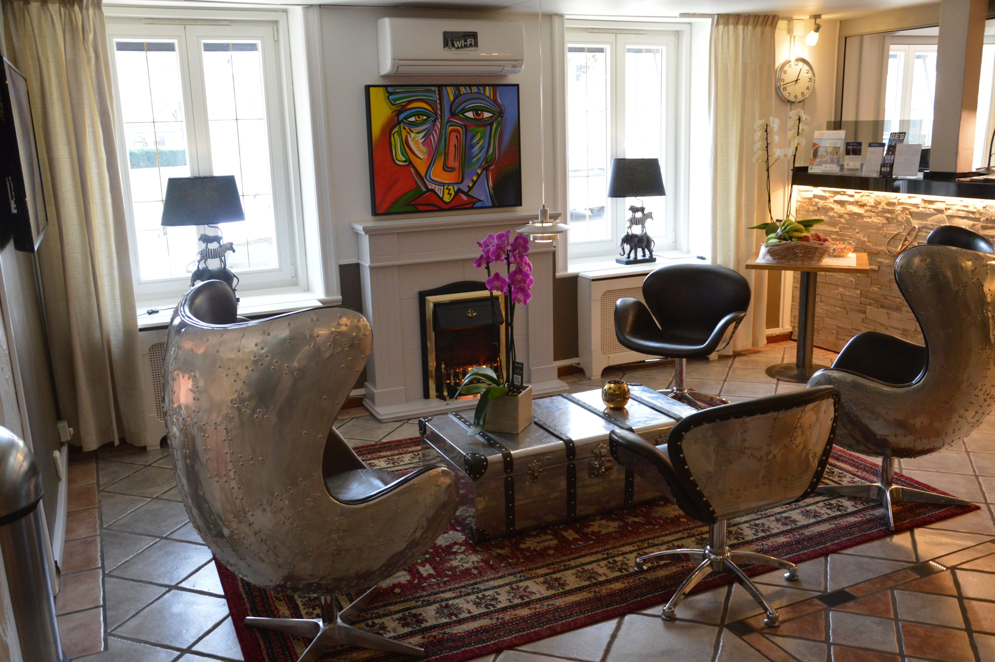 Una sala de estar moderna con chimenea, dos sillones, una mesa de centro y un cuadro en la pared.