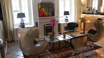 Una sala de estar moderna con chimenea, dos sillones, una mesa de centro y un cuadro en la pared.
