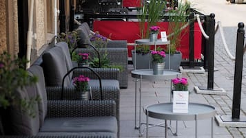 An outdoor seating area with wicker furniture and potted plants.