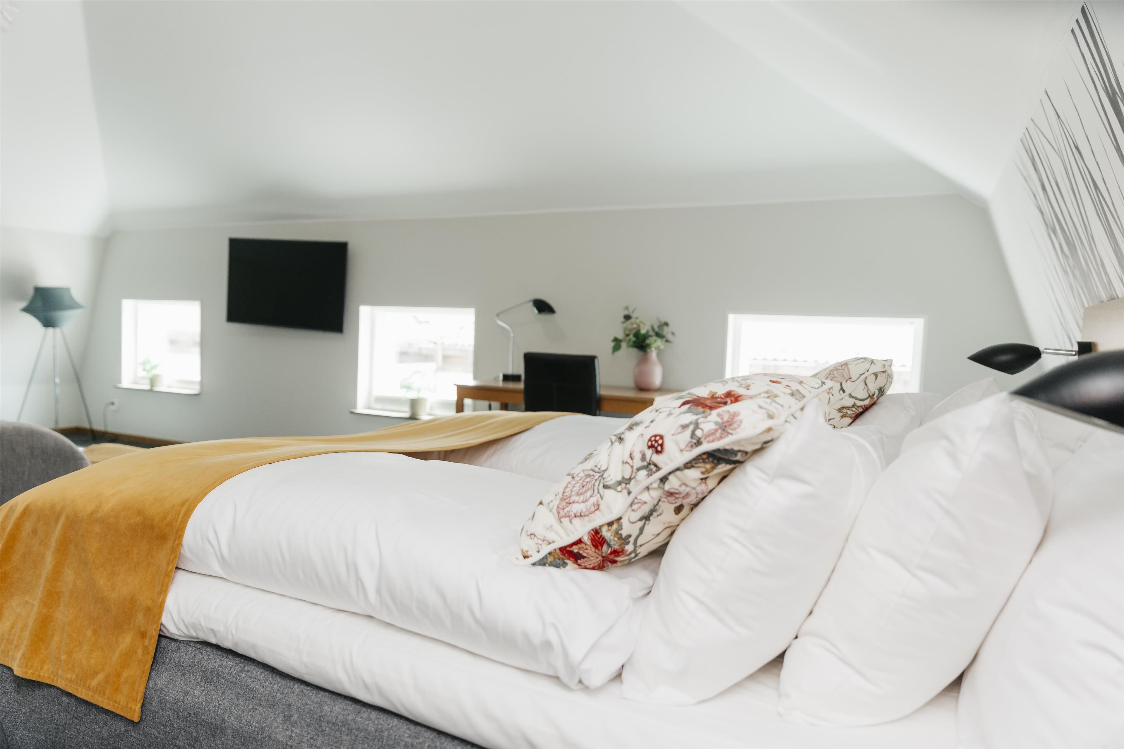 Une chambre à coucher avec un lit, un bureau, une chaise, une lampe et une fenêtre.
