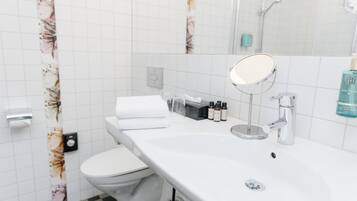 Un baño moderno con un lavamanos, espejo y retrete blancos.