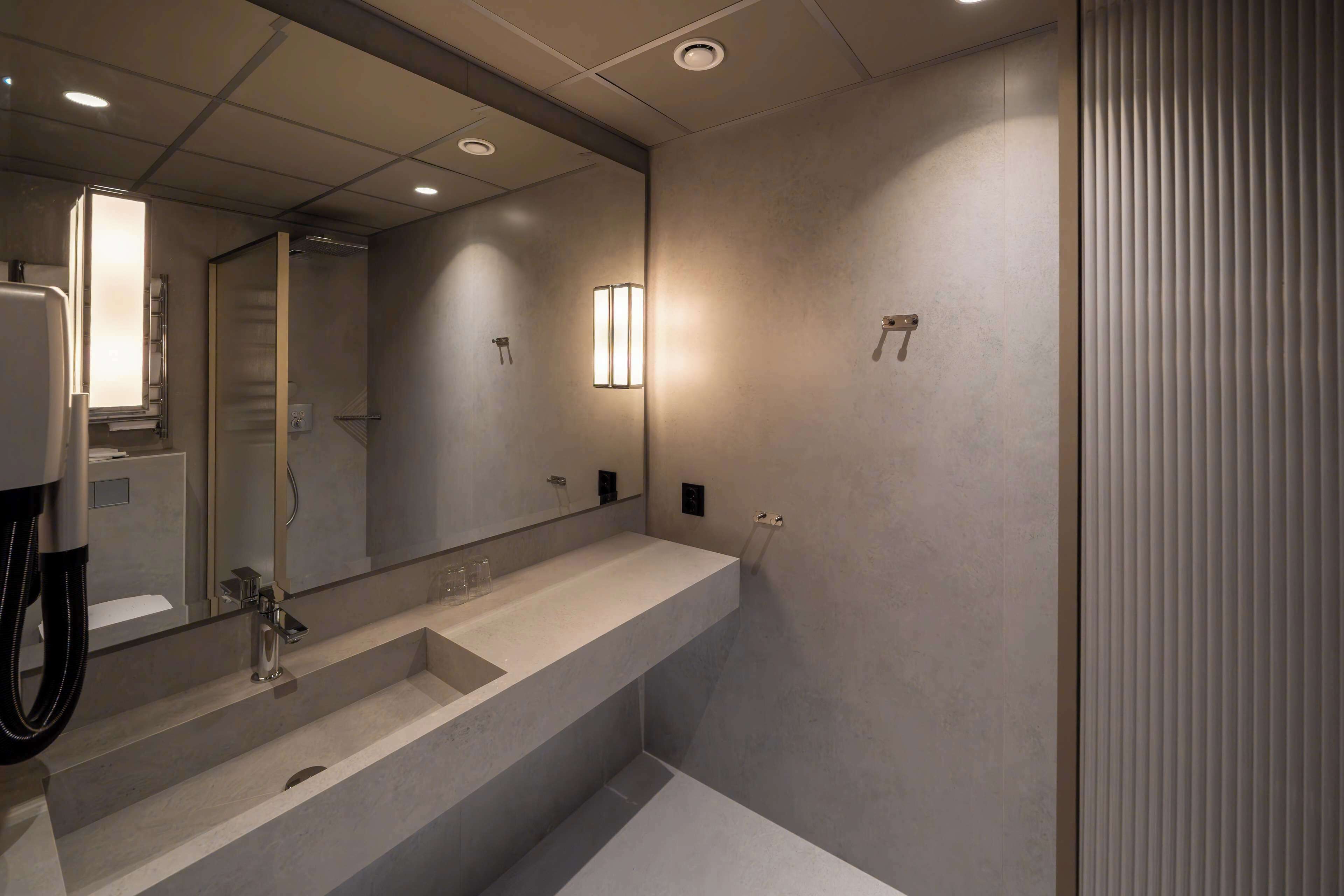 Un baño moderno con un espejo grande, dos lavamanos y una zona de ducha.