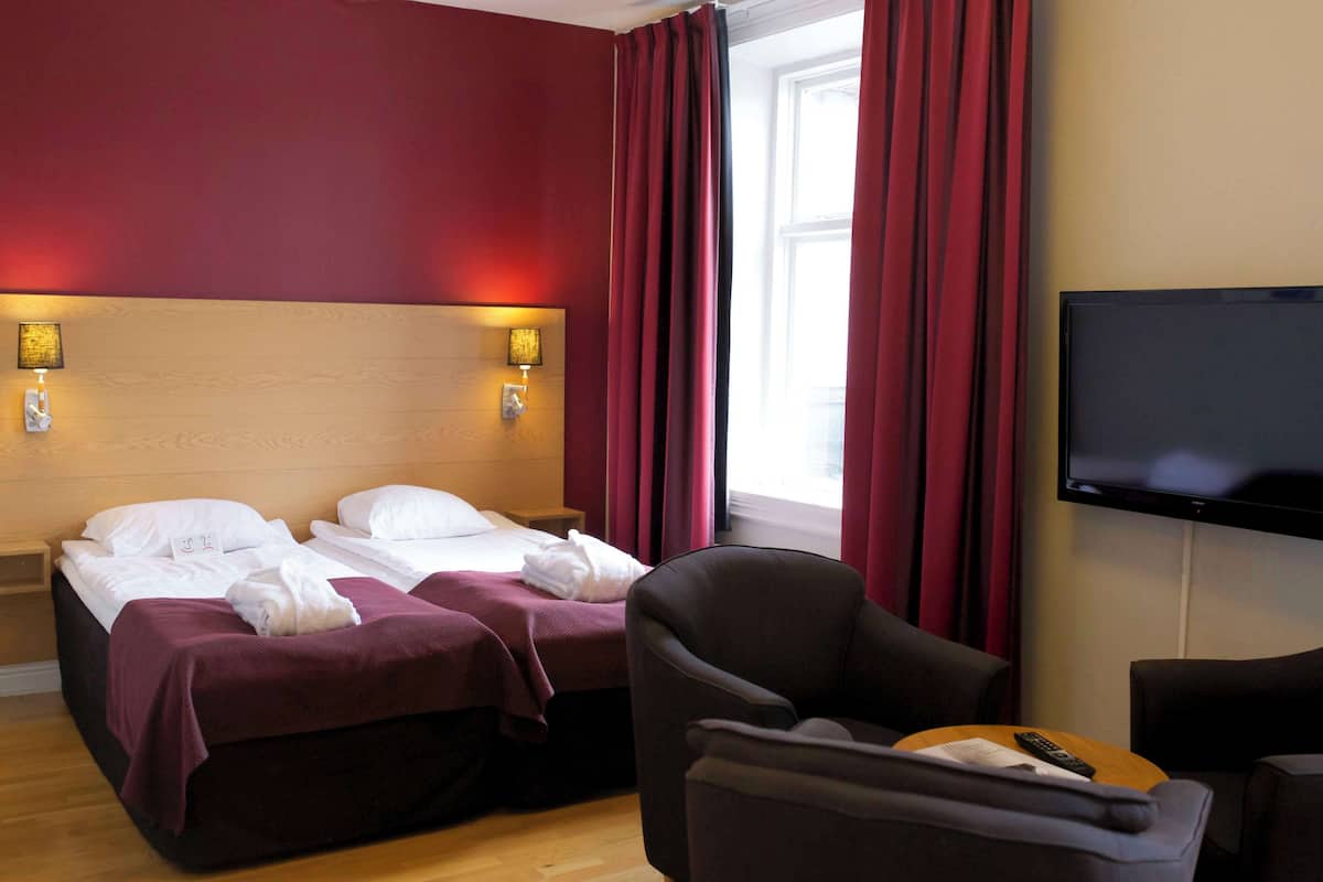 A hotel room with two beds, a TV, and a chair.