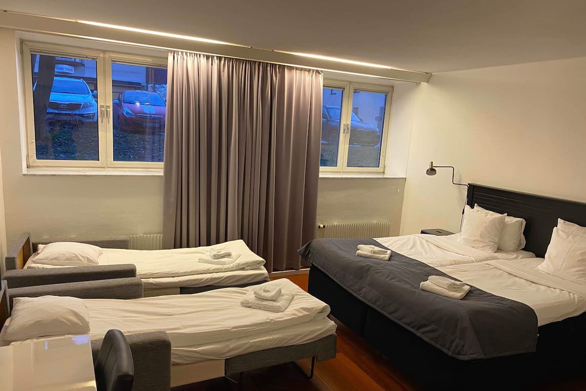 Une chambre d’hôtel avec deux lits simples, un grand lit, un bureau et une chaise.