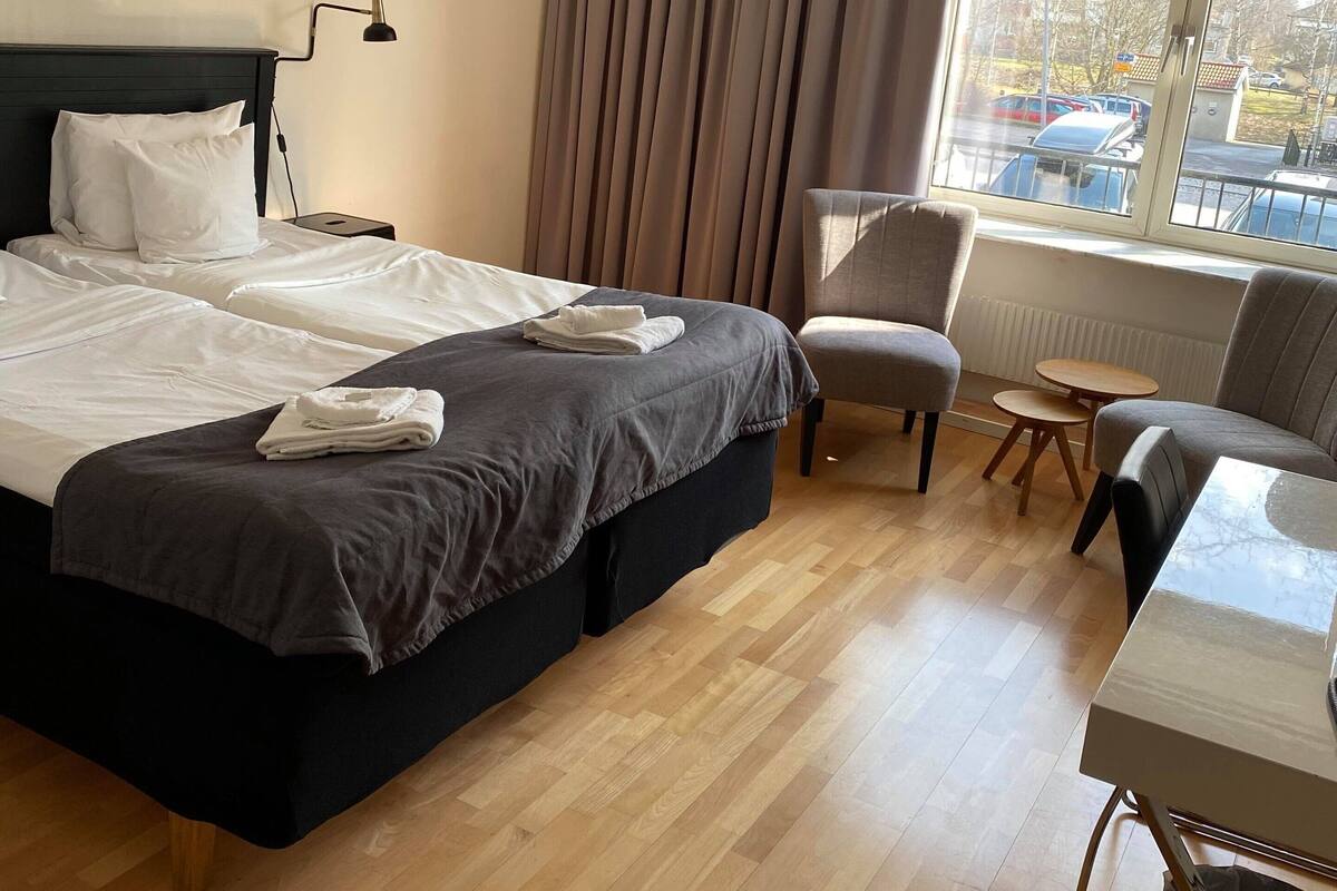 Une chambre d’hôtel avec un lit, une chaise, une table et une fenêtre donnant sur des voitures garées.