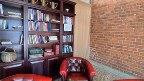 A library with leather armchairs, a round table, and bookshelves filled with books. - Hotell Alfred Nobel (Karlskoga)