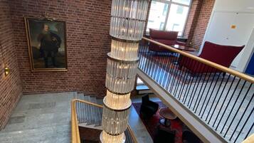 A multi-level interior with a central spiral staircase, brick walls, and a chandelier.