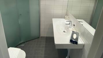 Baño con lavamanos, espejo y retrete blancos.