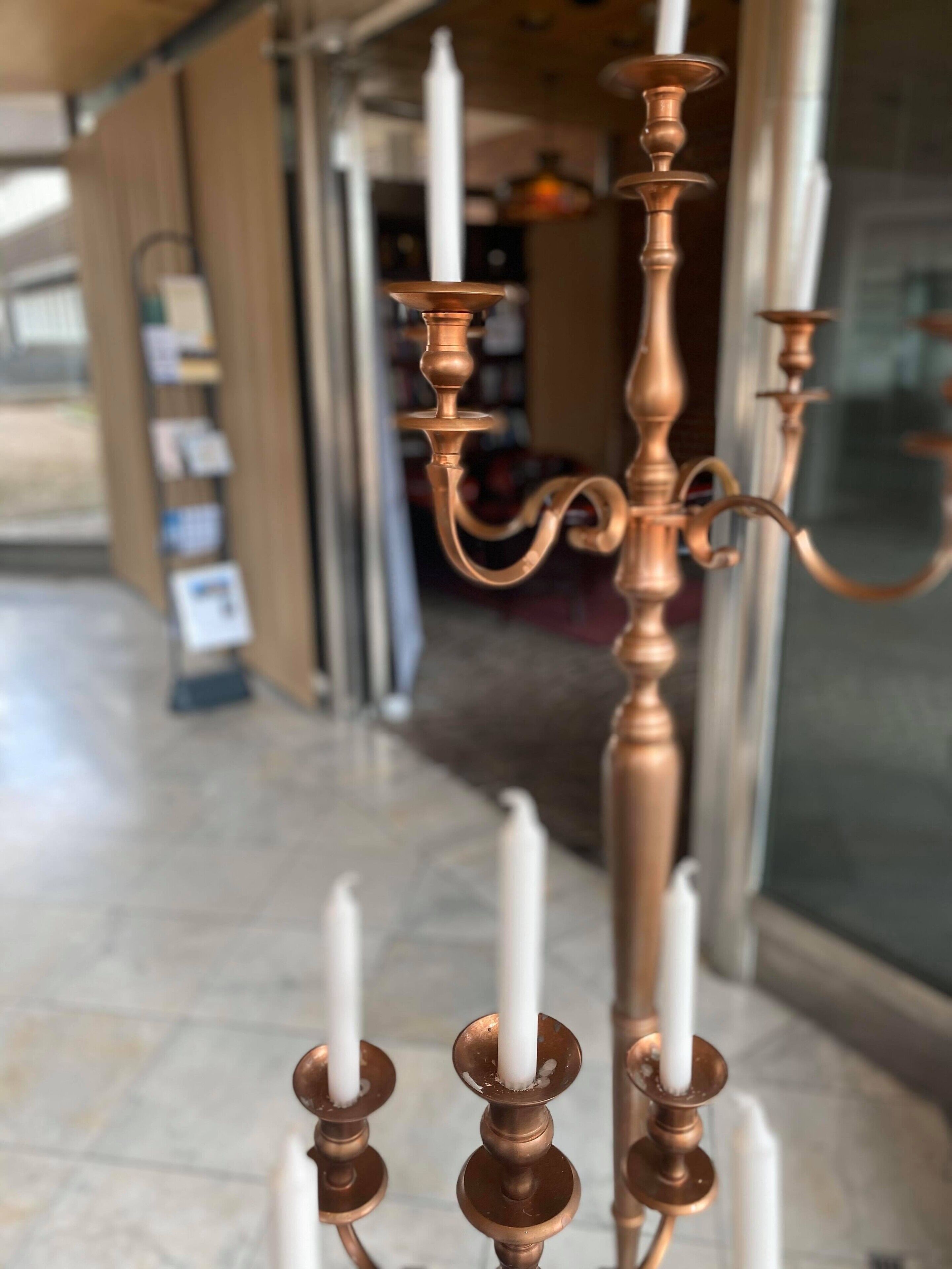 A chandelier with multiple candle holders and white candles.