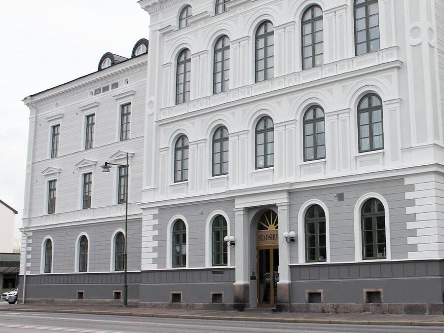 A large, white building with multiple arched windows and a prominent entrance labeled "Stadshuset."
