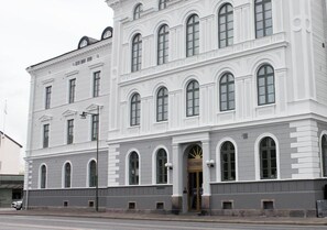 Un grande edificio bianco con numerose finestre ad arco e un ingresso ben visibile con la scritta 