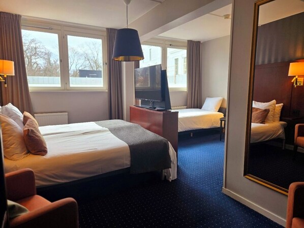 A hotel room with two beds, a TV, a desk, and a large mirror. - Vänerport Stadshotel (Mariestad)