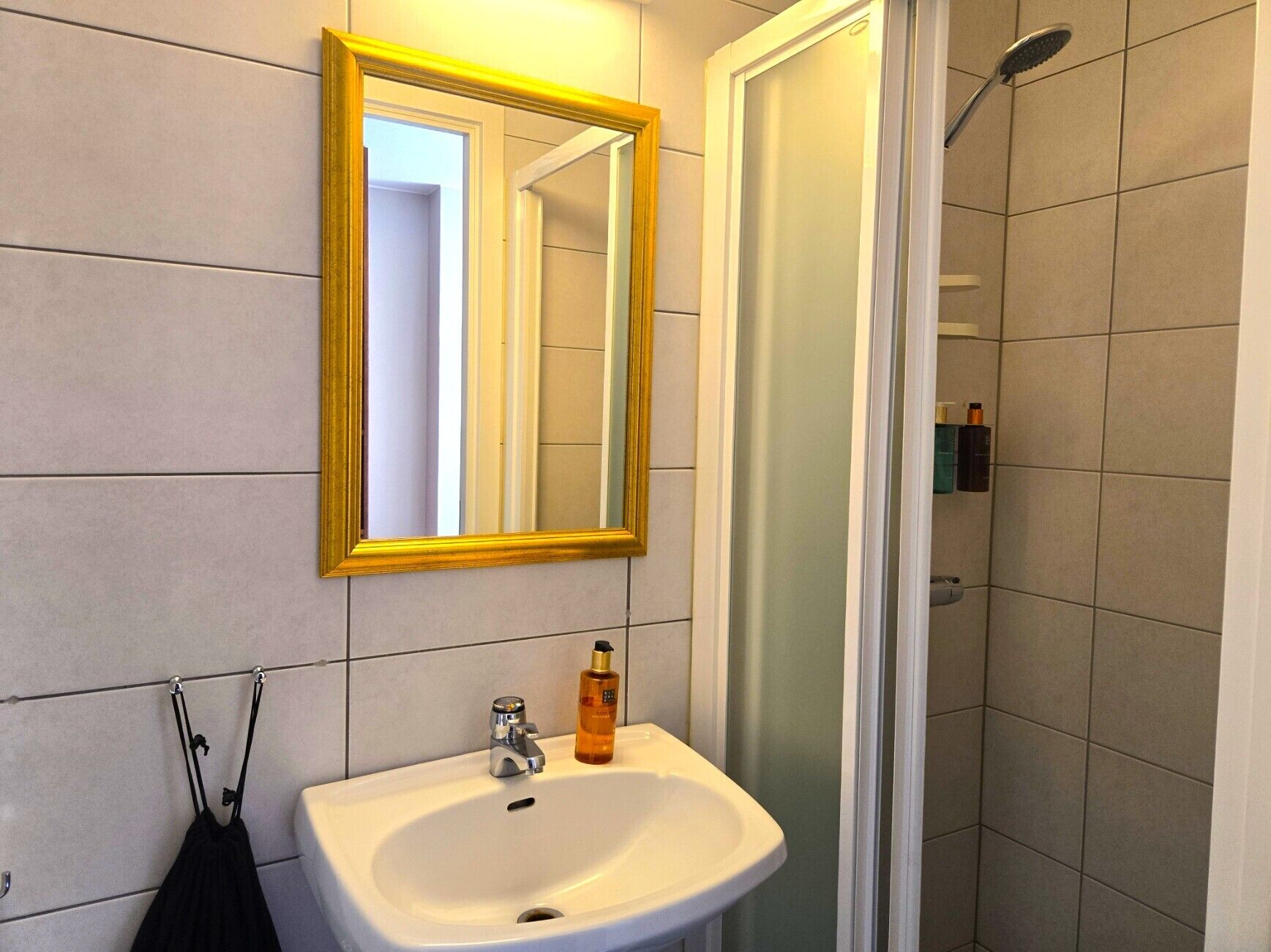 A bathroom with a white sink, a mirror with a gold frame, and a shower.