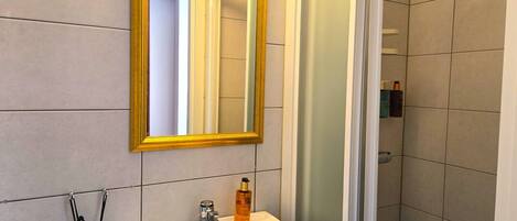 A bathroom with a white sink, a mirror with a gold frame, and a shower.