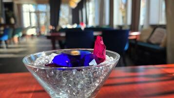 Una copa de martini con hielo y una decoración azul y roja sobre una mesa de madera en un restaurante.
