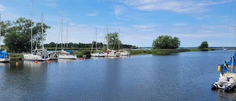 A marina with several sailboats docked, calm water, and a clear sky.
