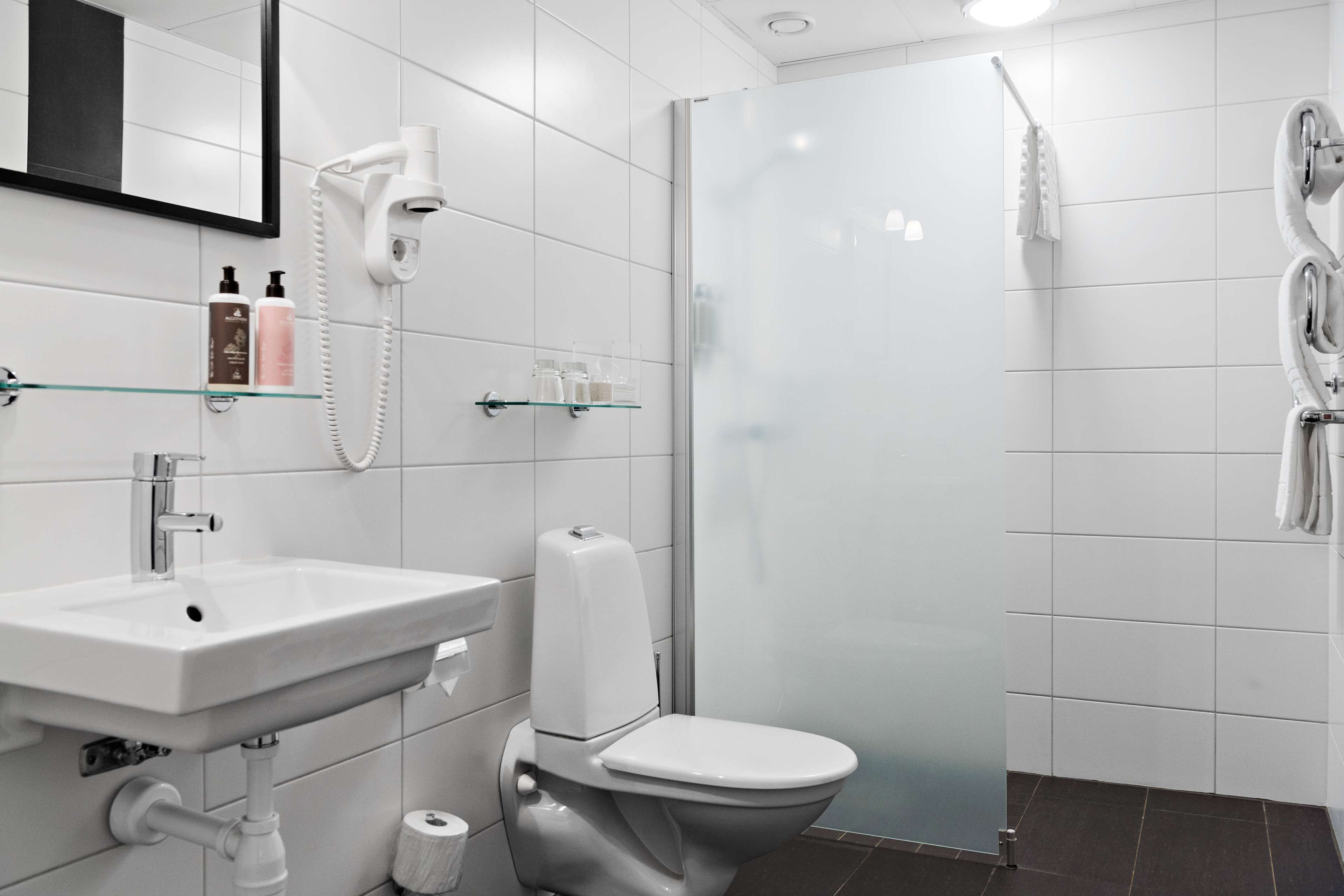 Un baño moderno con lavamanos, inodoro y cabina de ducha de vidrio.