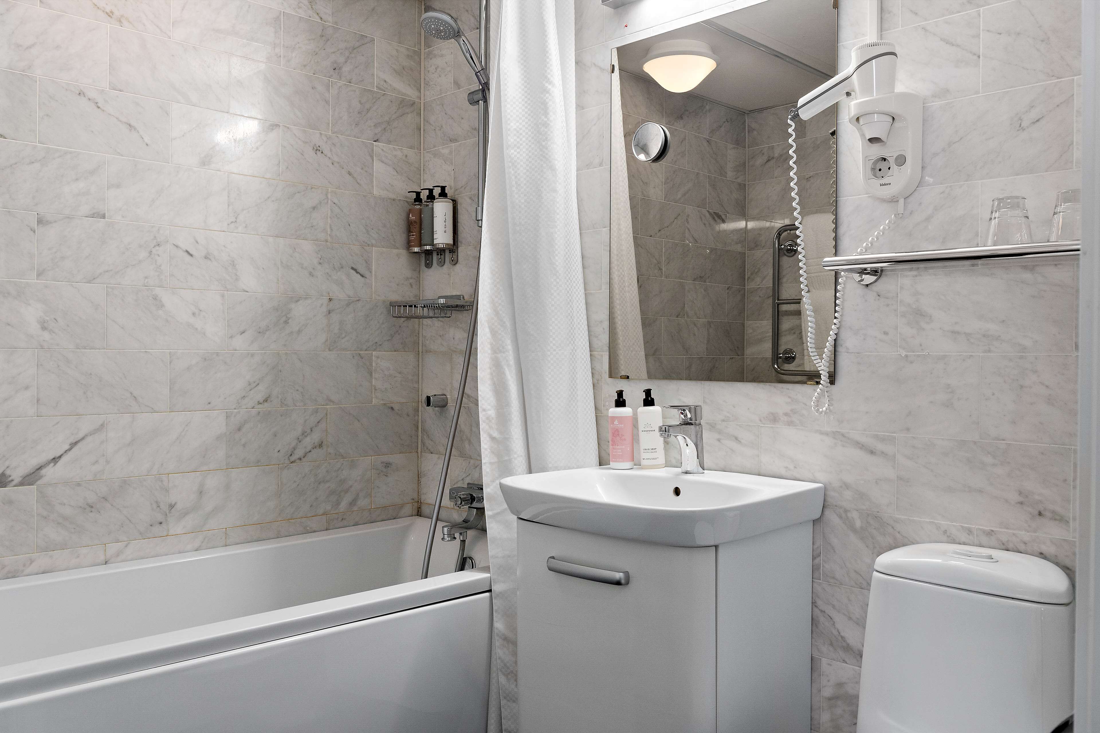 A bathroom with a bathtub, a sink, a toilet, and a shower area.
