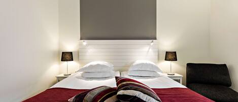 A hotel room with a bed, two bedside tables, a lamp, and a chair.