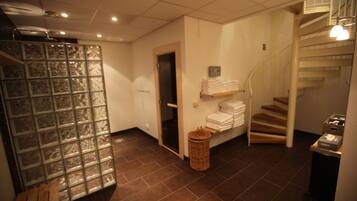 A hotel lobby with a glass partition, a staircase, and a shelf with folded towels.