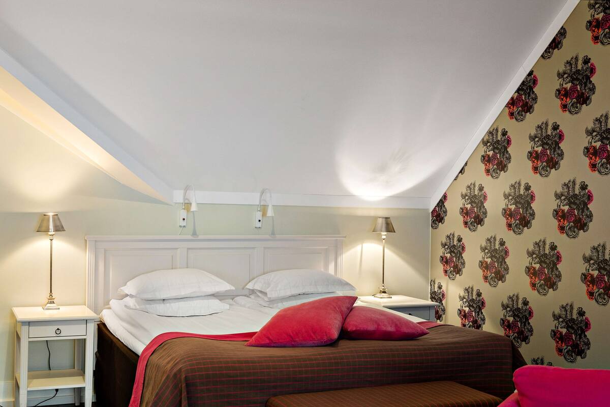 Un dormitorio con una cama, dos mesitas de noche y una pared decorada con estampado floral.