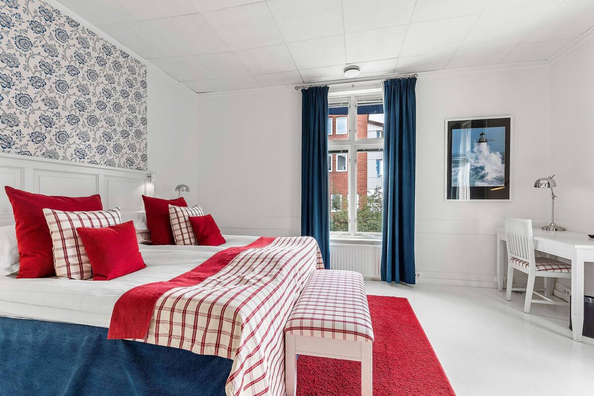 Un dormitorio con una cama grande, un escritorio y una ventana con cortinas.