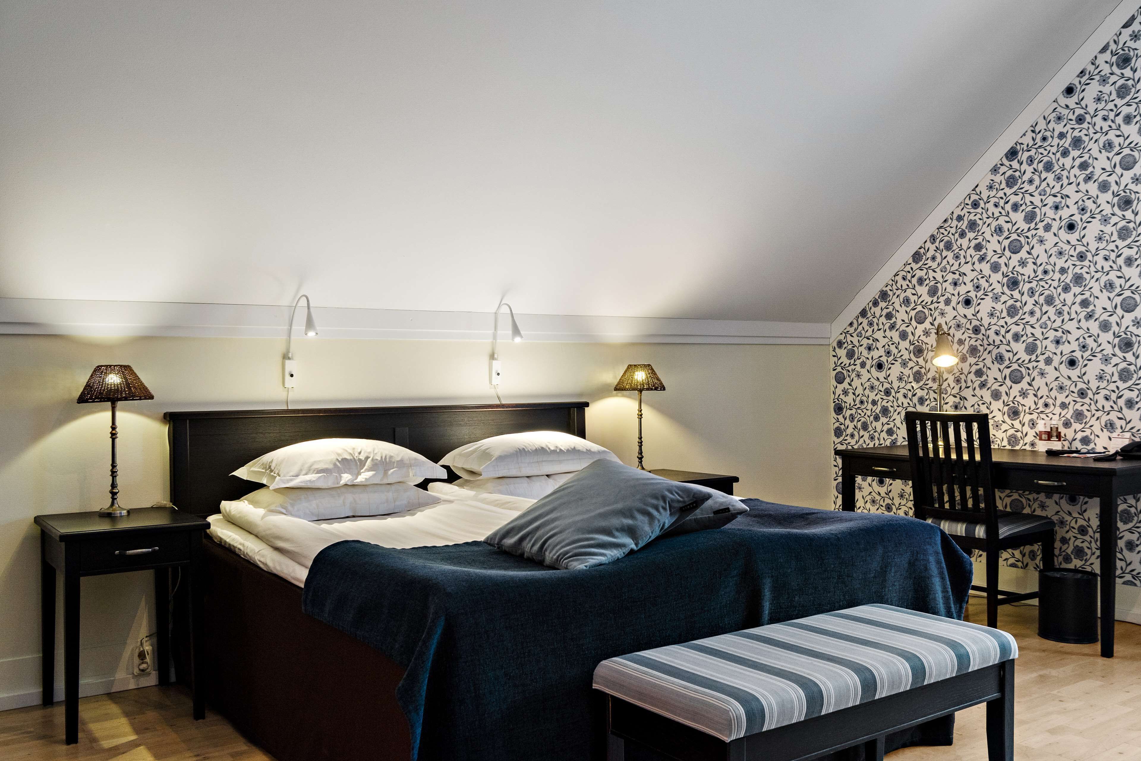 A bedroom with a bed, bedside tables, lamps, a desk, and a chair.