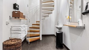 Un baño moderno con una escalera de madera, un lavabo y un espejo.