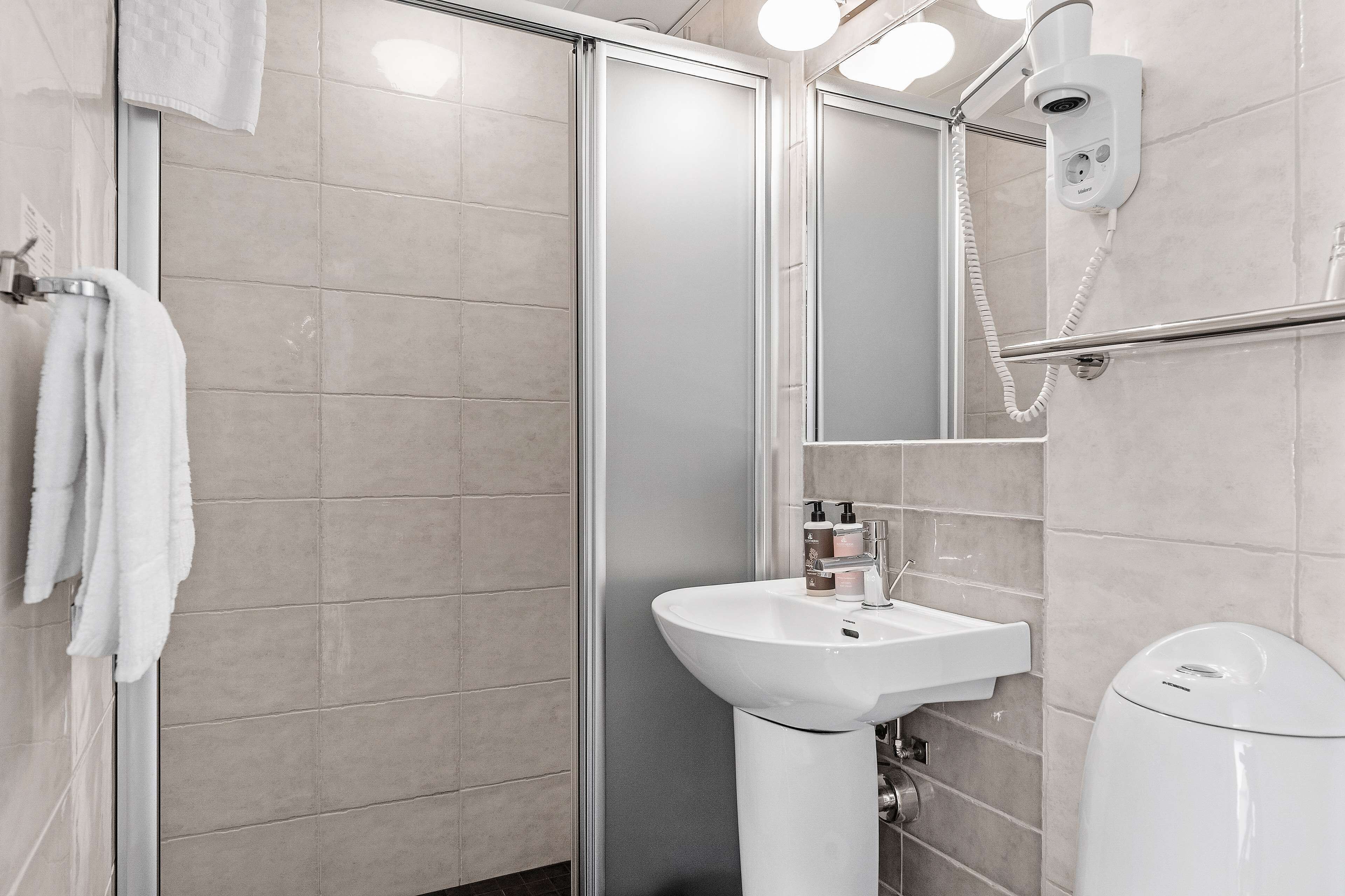 A modern bathroom with a glass shower enclosure, a white sink, and a toilet.