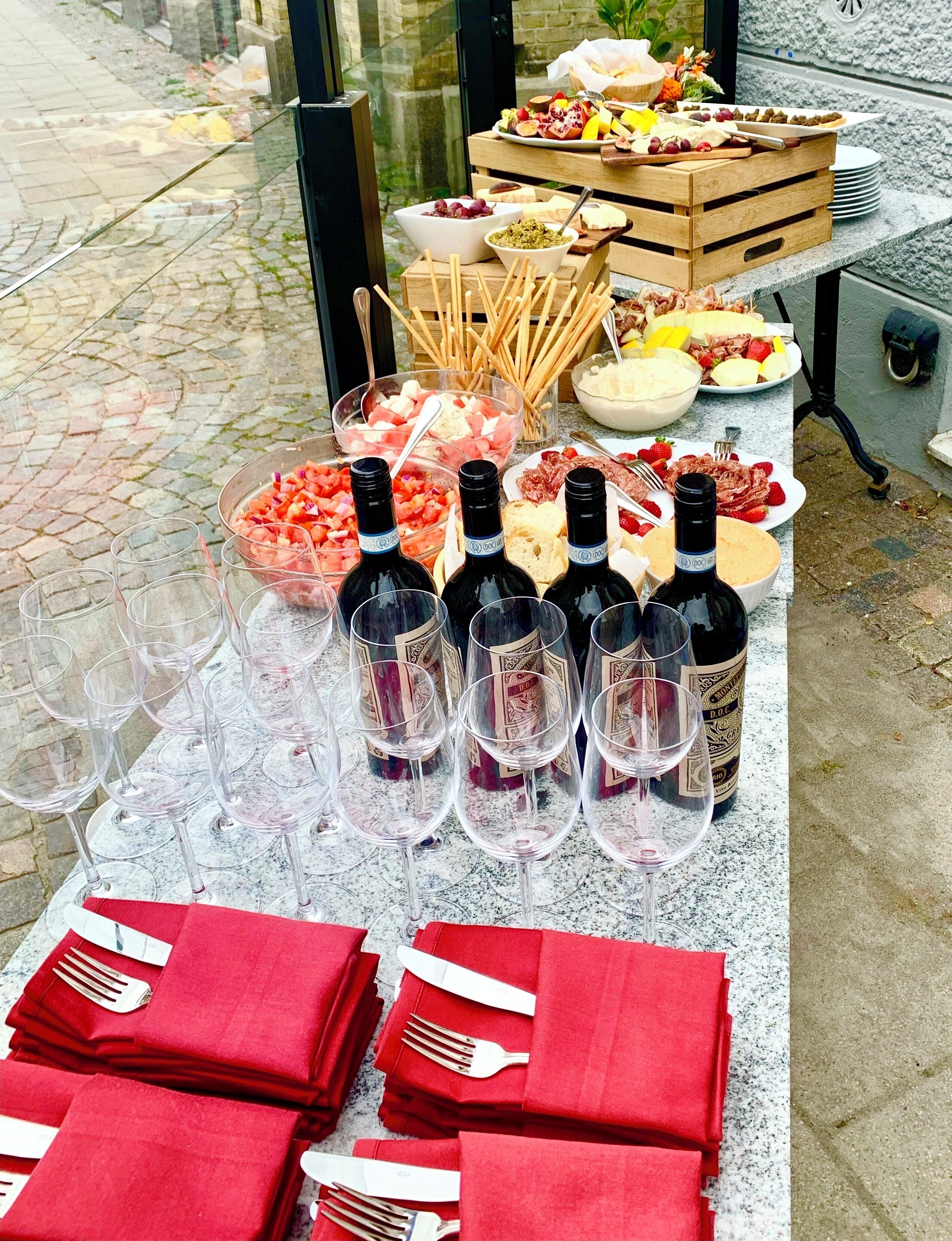 A table set with wine glasses, bottles, and red napkins.