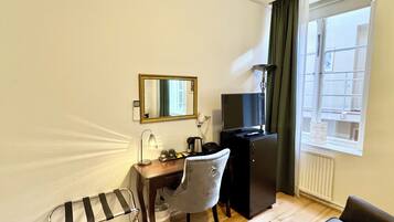 Une chambre d’hôtel équipée d’un bureau, d’une chaise, d’une télévision et d’une fenêtre avec des rideaux.