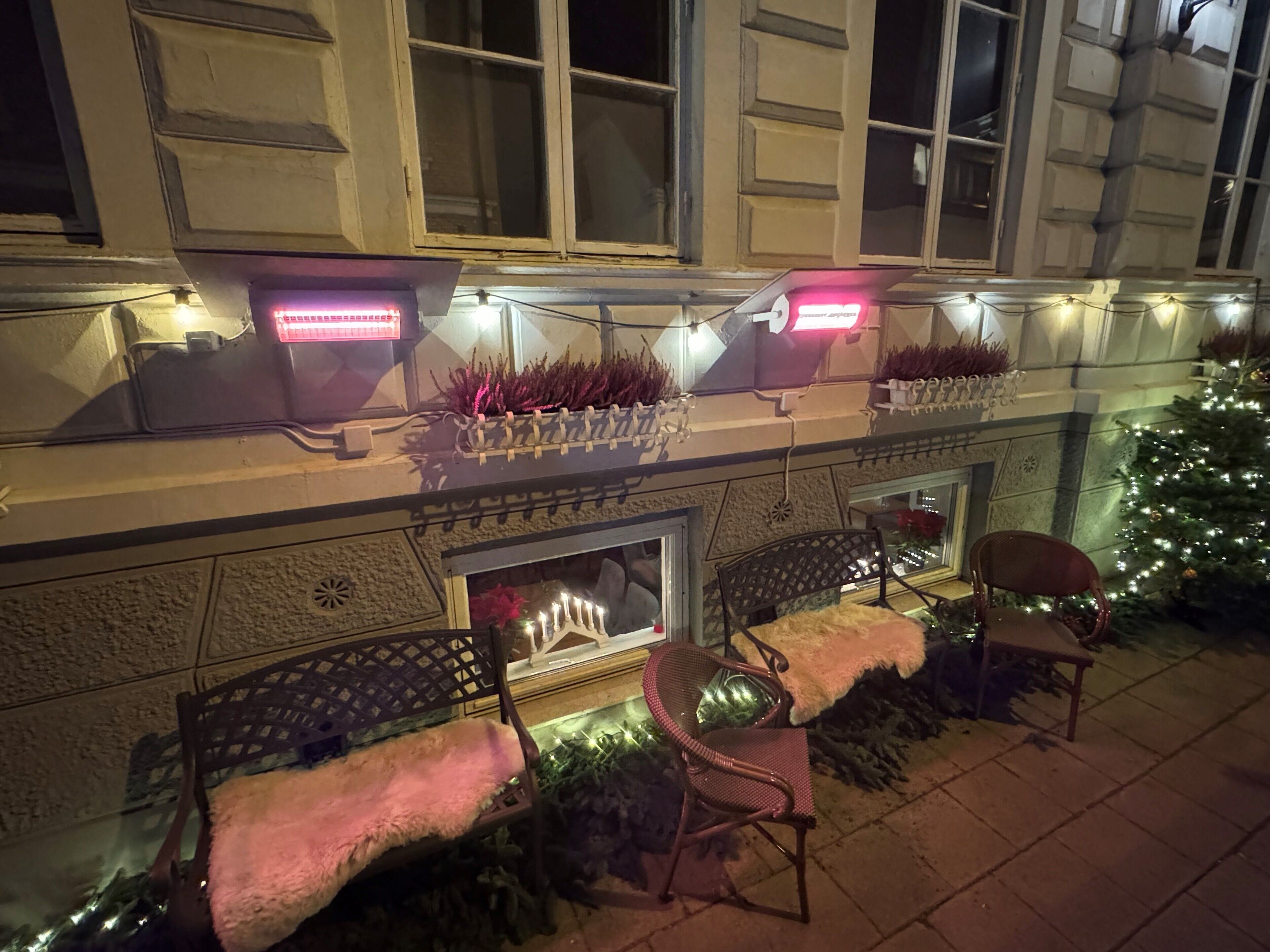 Et hotels ydre med pejs, udendørs siddepladser og et juletræ.