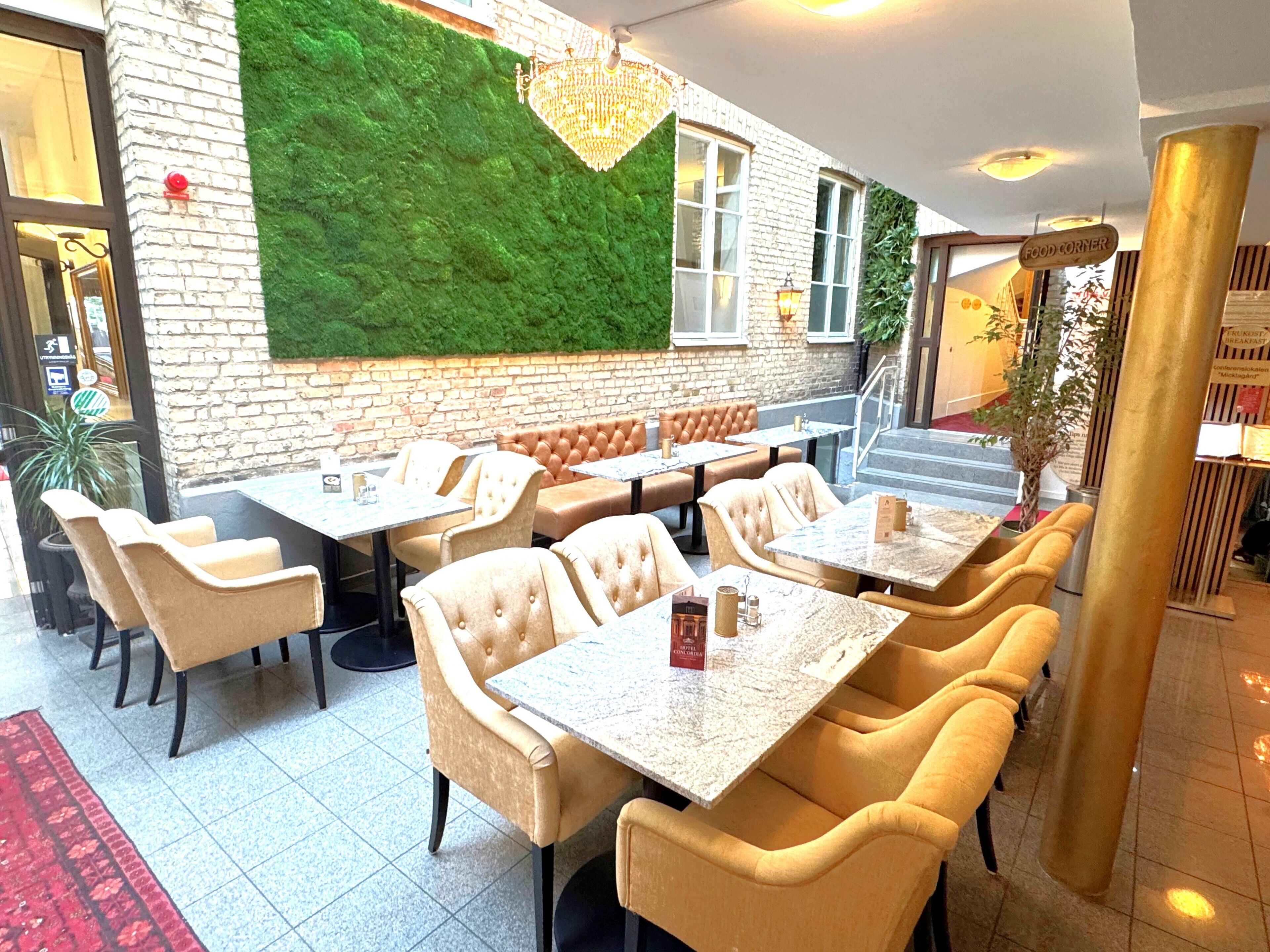 A restaurant with a green wall, brick exterior, and indoor seating with tables and chairs.