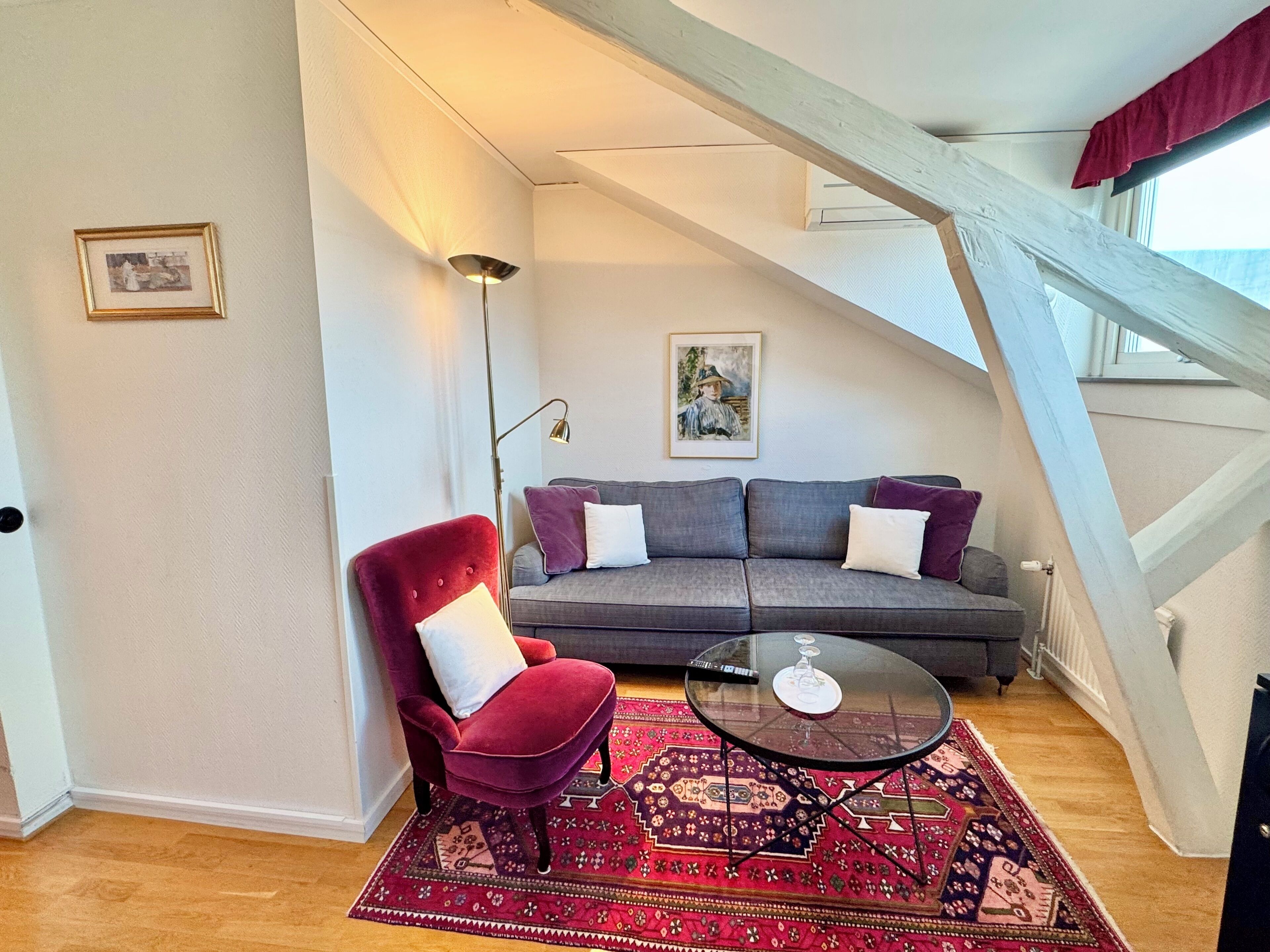 Una sala de estar moderna con una silla roja, un sofá gris y una mesa de centro de vidrio.