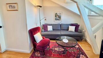 Una sala de estar moderna con una silla roja, un sofá gris y una mesa de centro de vidrio.