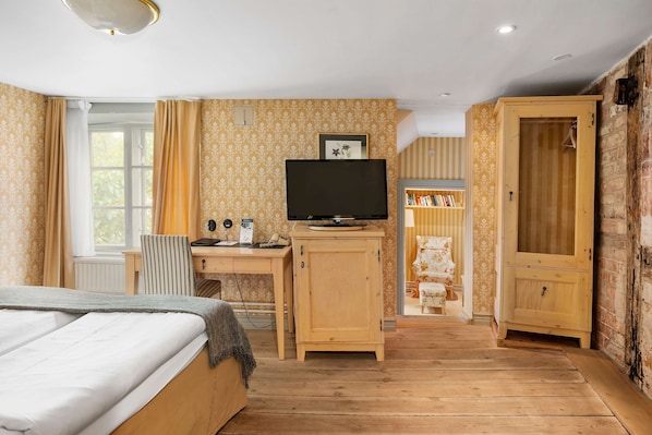 Un dormitorio con cama, escritorio con computadora, televisor y armario.