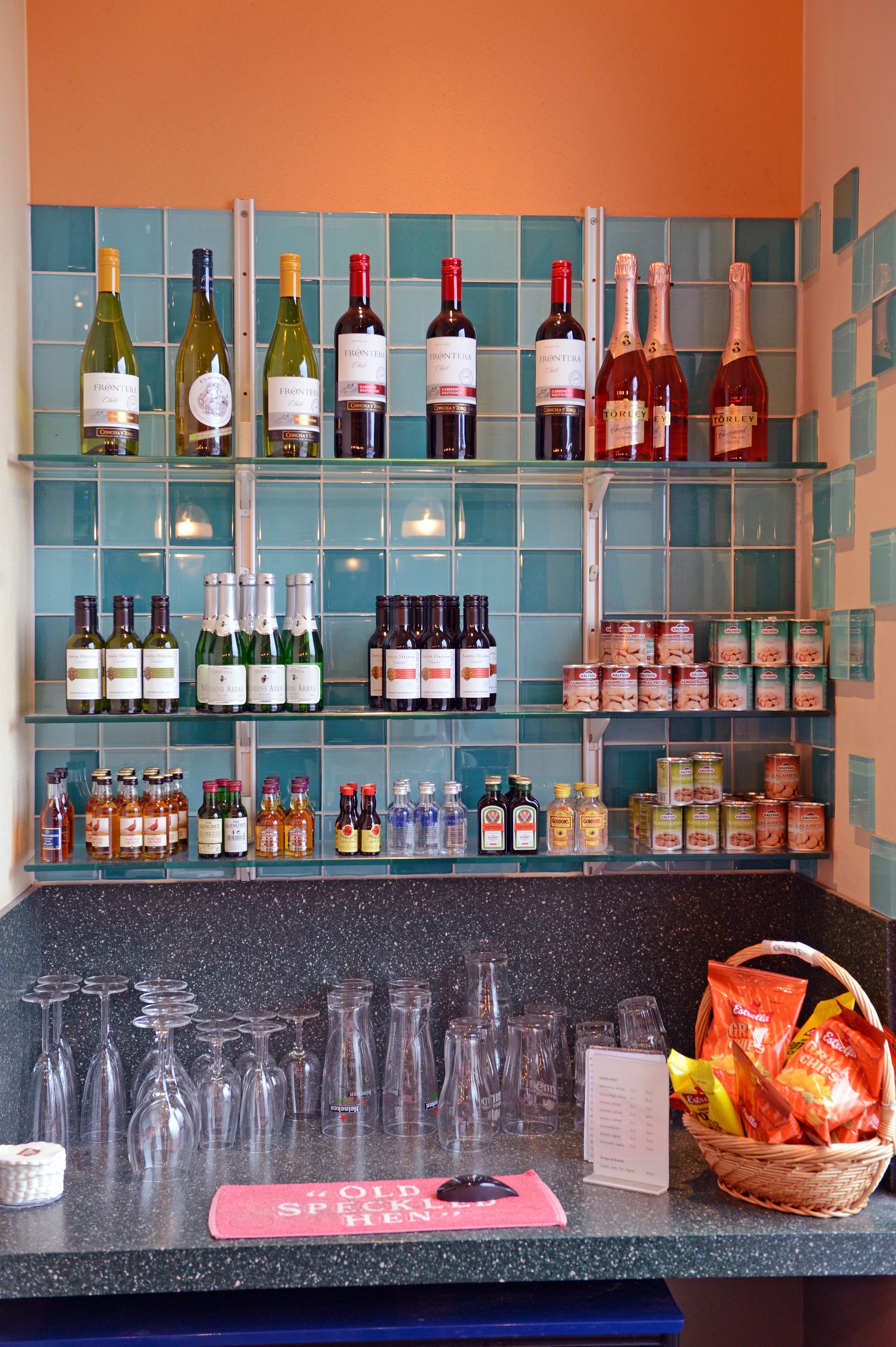 A wine and spirits display with various bottles and glasses on shelves and the counter.