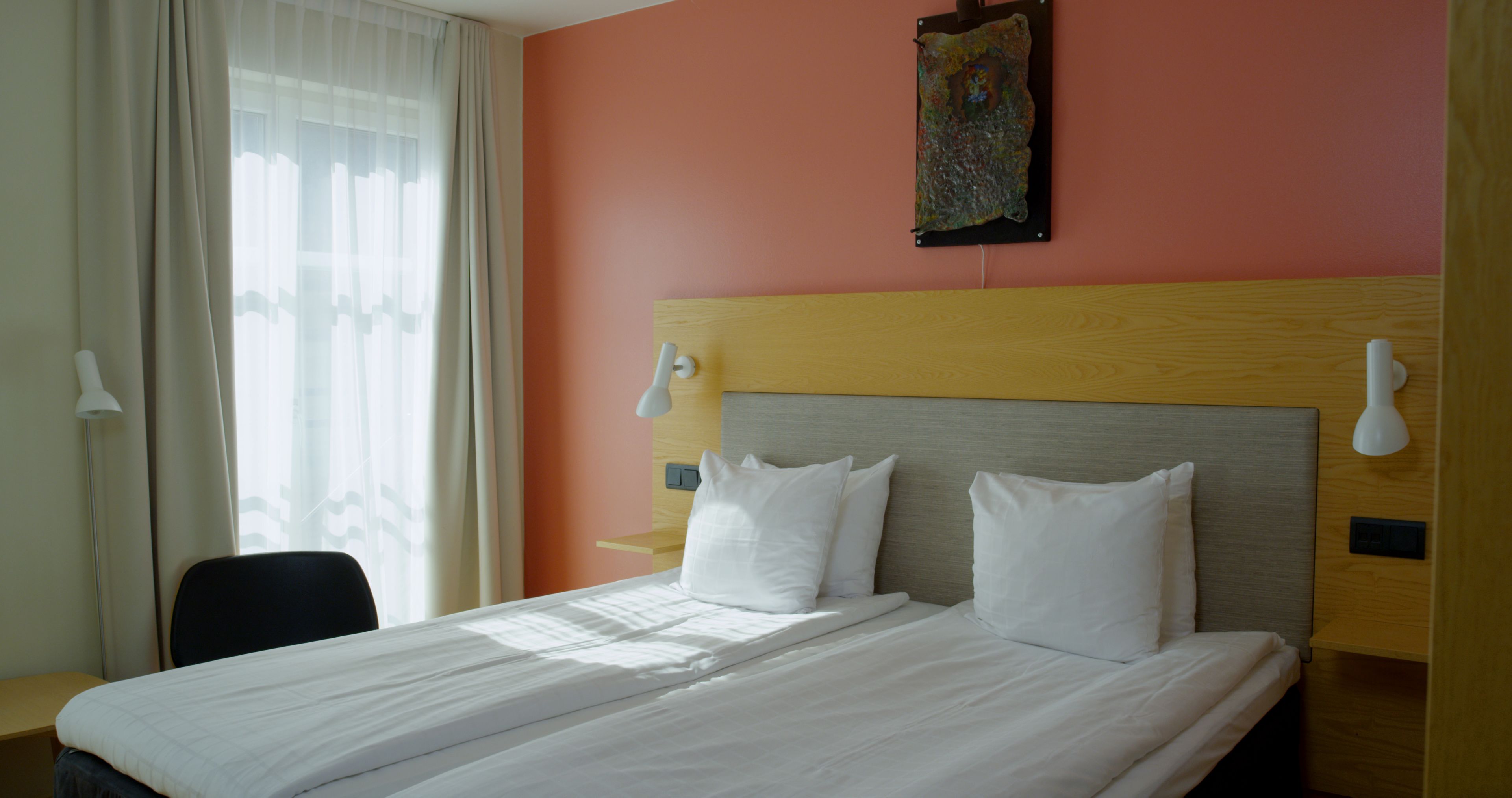 A hotel room with a large bed, two bedside tables, a desk, and a chair.