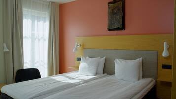 A hotel room with a large bed, two bedside tables, a desk, and a chair.