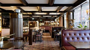 A restaurant interior with wooden tables, cushioned booths, and a patterned carpet. - Hotel Bishops Arms Mora (Mora)