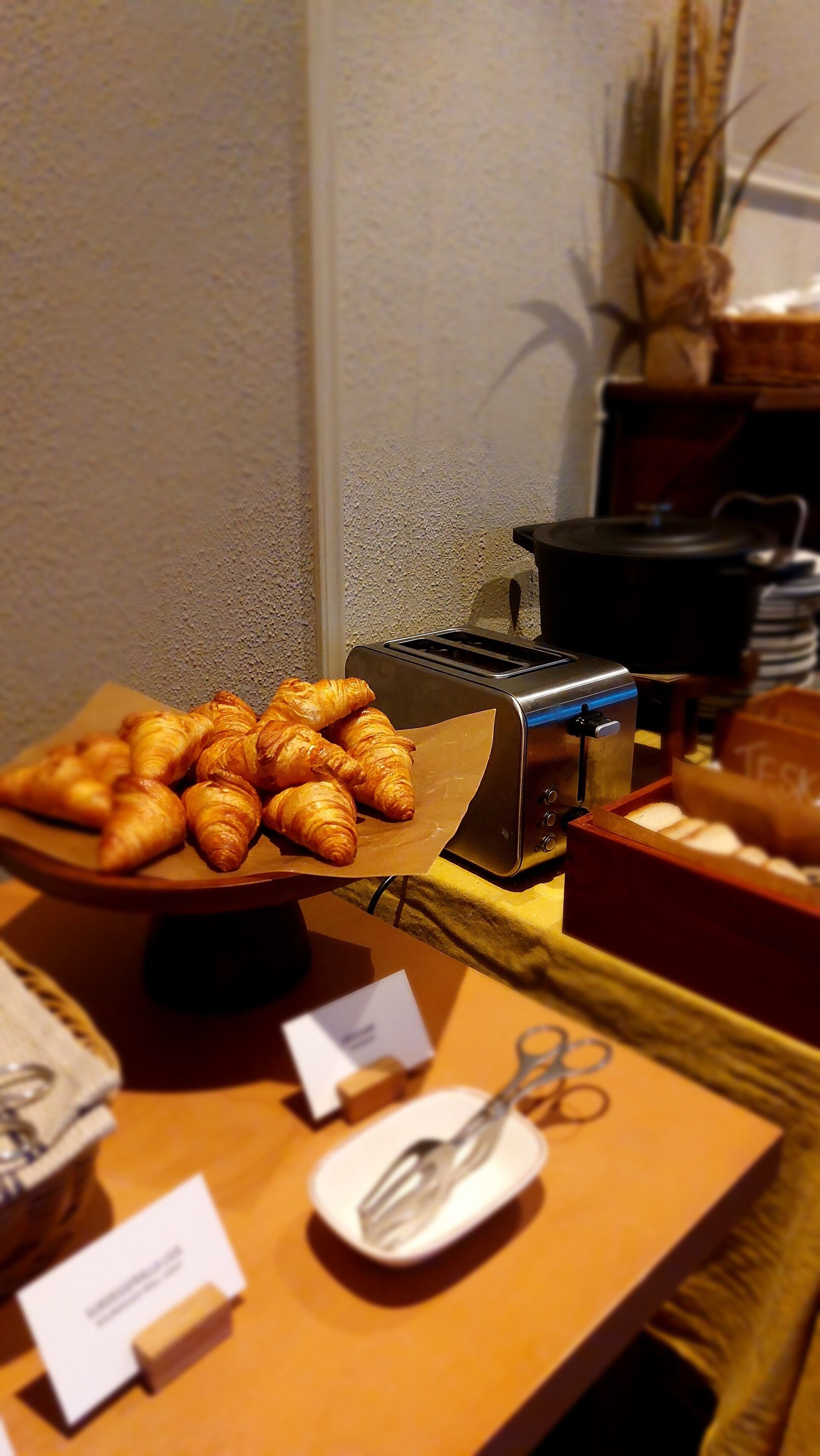 Mesa de buffet com croissants e uma torradeira.
