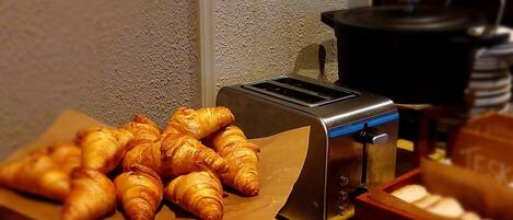 A buffet table with croissants and a toaster.