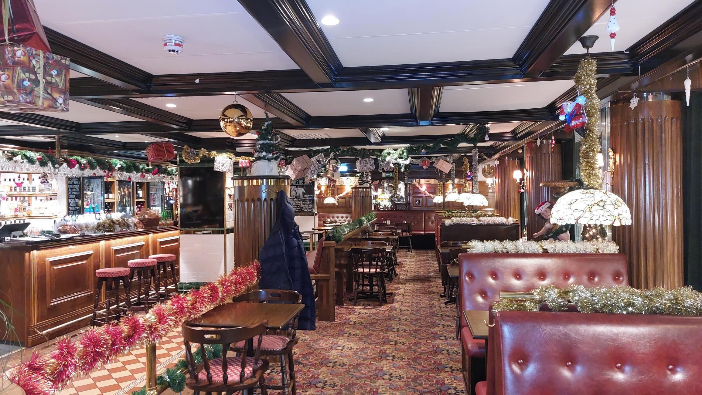 Un restaurante con barra, cabinas y alfombra estampada.